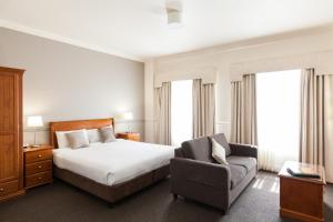 a hotel room with a bed and a chair at Majestic Tynte Street Apartments in Adelaide
