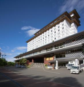 a large white building with cars parked in a parking lot at Kitayuzawa Mori no soraniwa in Date