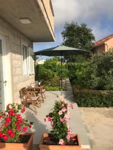 a patio with a table and an umbrella and flowers at Sweet Dreams - Studio Apartment in Dubrovnik