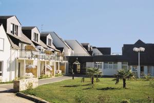 una fila di case con palme nel cortile di Résidence Pierre & Vacances La Voile d'Or a Île-aux-Moines