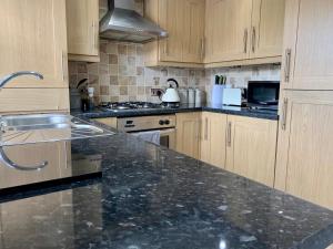 - une cuisine avec des placards en bois et un plan de travail en granit dans l'établissement Castle Cottage, à Harrogate 13 autres photos