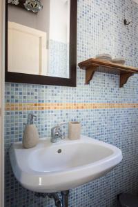 een witte wastafel in een blauwe betegelde badkamer bij Case d'Oriente in Modica