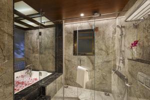 a bathroom with a shower and a sink and a tub at Lazy Lagoon, Baga A Lemon Tree Resort, Goa in Baga