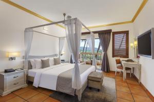 a bedroom with a bed and a desk and a television at Lazy Lagoon, Baga A Lemon Tree Resort, Goa in Baga