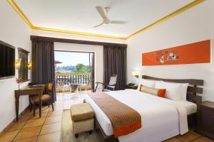 a bedroom with a bed and a desk and a balcony at Lazy Lagoon, Baga A Lemon Tree Resort, Goa in Baga