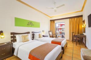 a hotel room with two beds and a table and chairs at Lazy Lagoon, Baga A Lemon Tree Resort, Goa in Baga