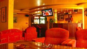a bar with red chairs and a tv in a room at Family Hotel Silvestar in Veliko Tŭrnovo