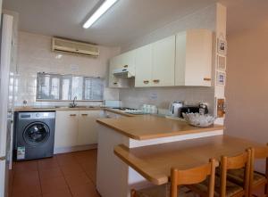 - une cuisine avec des placards blancs, une table et un lave-vaisselle dans l'établissement 18 The Shades Umhlanga Rocks, à Durban