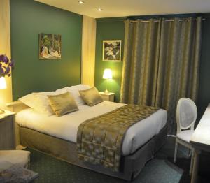 a hotel room with a bed with green walls at L'Hôtel Le Cheval Noir in Moret-sur-Loing