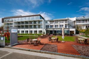 a building with tables and chairs in front of it at Hotel Yacht Wellness & Business in Siófok