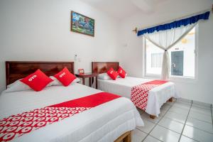 2 camas en una habitación con almohadas rojas y blancas en OYO Hotel Posada San Vicente, Huatulco en Santa María Huatulco