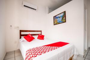 Un dormitorio con una cama con almohadas rojas. en OYO Hotel Posada San Vicente, Huatulco en Santa María Huatulco