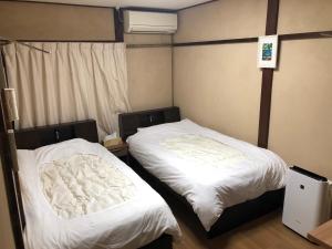 two beds in a room with white sheets at Guest House Ga-Jyun in Kyoto