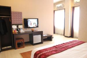 a bedroom with a bed and a desk with a television at Hotel Roditha Banjarbaru in Banjarbaru