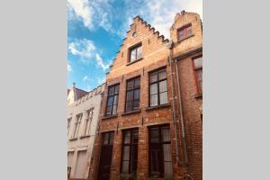 an old brick building with a turret on a street at Huyze Cordoeanier in Bruges