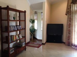 a living room with a television and a book shelf at Silvikris Villa in Colombo