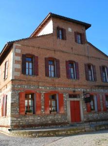 un antiguo edificio de ladrillo con puertas y ventanas rojas en Hotel Koukouli en Souflíon