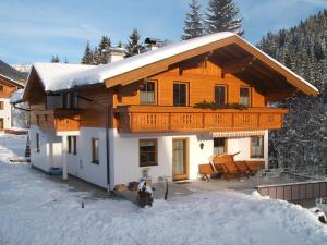 a wooden house with a balcony in the snow at Haus Sonnental in Filzmoos