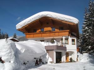 a building covered in snow with a pile of snow at Haus Sonnental in Filzmoos