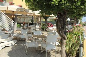 a patio with white chairs and tables and a tree at Hotel Sedonia in Cervia