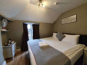 um quarto com uma cama com duas toalhas em Belgravia Rooms Hotel em Londres