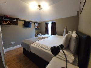 um quarto com uma cama e uma secretária com um candeeiro em Belgravia Rooms Hotel em Londres
