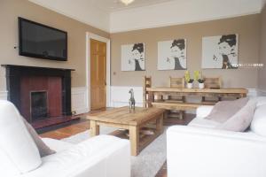 a living room with white furniture and a flat screen tv at Windsor Street Apartment in Edinburgh