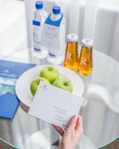 a person holding a piece of paper in front of a plate of apples at Four Elements Perm in Perm