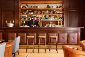 a man standing behind a bar in a restaurant at Hôtel Barrière Le Westminster in Le Touquet-Paris-Plage