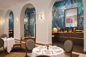 a dining room with tables and chairs and a wall mural at Hôtel Barrière Le Westminster in Le Touquet-Paris-Plage