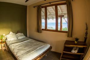 1 dormitorio con cama y ventana con vistas al océano en Hotel Kambutaleko en Cambutal