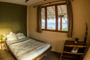 a bedroom with a bed and a window with the ocean at Hotel Kambutaleko in Cambutal