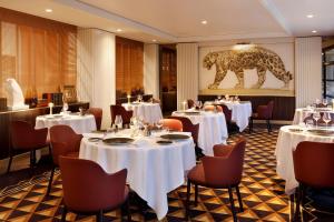 a restaurant with white tables and chairs and a lion on the wall at Hôtel Barrière Le Westminster in Le Touquet-Paris-Plage