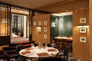 a restaurant with tables and chairs and a green wall at Hôtel Barrière Le Westminster in Le Touquet-Paris-Plage