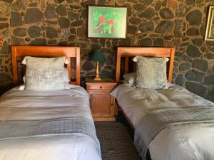 duas camas num quarto com paredes de pedra em Lepêllê Lodge em Burgersfort