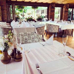 um restaurante com mesas brancas e cadeiras com toalha de mesa branca em Maria Penzion & Restaurant em Trenčín
