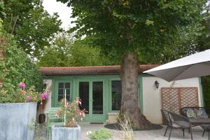 una casa con una puerta verde y un árbol en L'Orée de Giverny, en Limetz