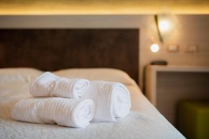 3 asciugamani laminati posti sopra un letto di Hotel Garnì Villa Magnolia a Torbole
