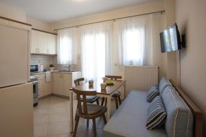 a kitchen and a living room with a couch and a table at Santorini Med Homes - Sunday Apartment in Mesaria