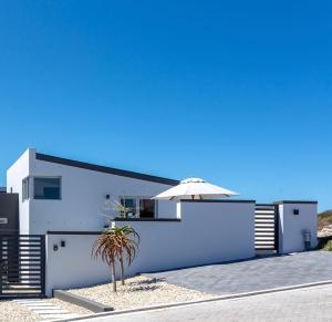 a white house with an umbrella and a palm tree at Pelicans View in Yzerfontein