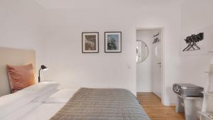 a white bedroom with a bed and pictures on the wall at Beethoven Hotel Dreesen - furnished by BoConcept in Bonn