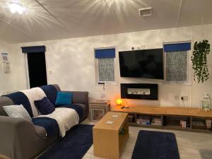 a living room with a couch and a flat screen tv at Loxley's Devon Lodge in Brixham
