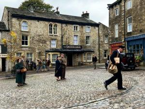 Un homme marchant dans une rue pavée d'une vieille ville dans l'établissement The Devonshire Grassington, à Grassington