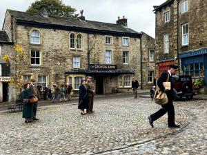 a man walking down a cobblestone street in an old town at The Devonshire Grassington in Grassington