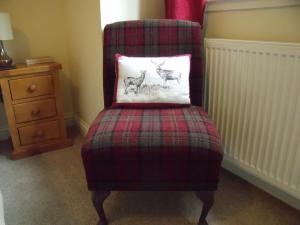 
a red chair in a room next to a dresser at Beechwood Cottage B&B in Glencoe
