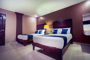 a bedroom with two beds with blue and white pillows at Capital O Hotel Diro, Monterrey in Monterrey