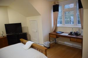 a bedroom with a bed and a desk and a window at The Bell and Bottle in Maidenhead