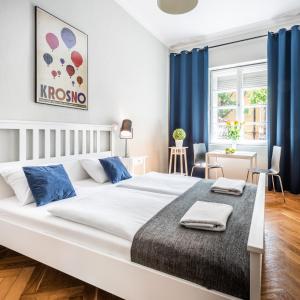 - une chambre avec un grand lit blanc et des rideaux bleus dans l'établissement Old Town Apart, à Cracovie