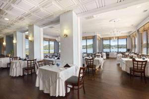 um restaurante com mesas e cadeiras brancas e janelas em Wyndham Garden Lake Guntersville em Guntersville