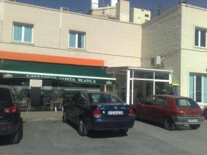 Hotel Costa Blanca في Granja de Rocamora: سيارتين متوقفتين في موقف للسيارات امام مبنى
